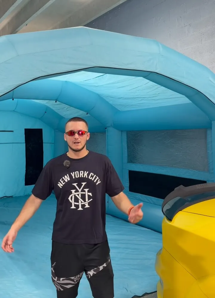 Fima standing inside the shop’s blue inflatable paint booth